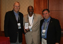 Ohio State University Associate Vice President and Director of Athletics Gene Smith (center) accepted the United States Sports Academy’s 2010 Carl Maddox Sports Management Award Thursday, June 16 at the National Association of Collegiate Directors of Athletics annual convention in Orlando. Dr. Gary Cunningham (left), an Academy Board of Trustees member and 2005 winner of the Maddox award, made the presentation with Academy Vice President Dr. T.J. Rosandich (right).